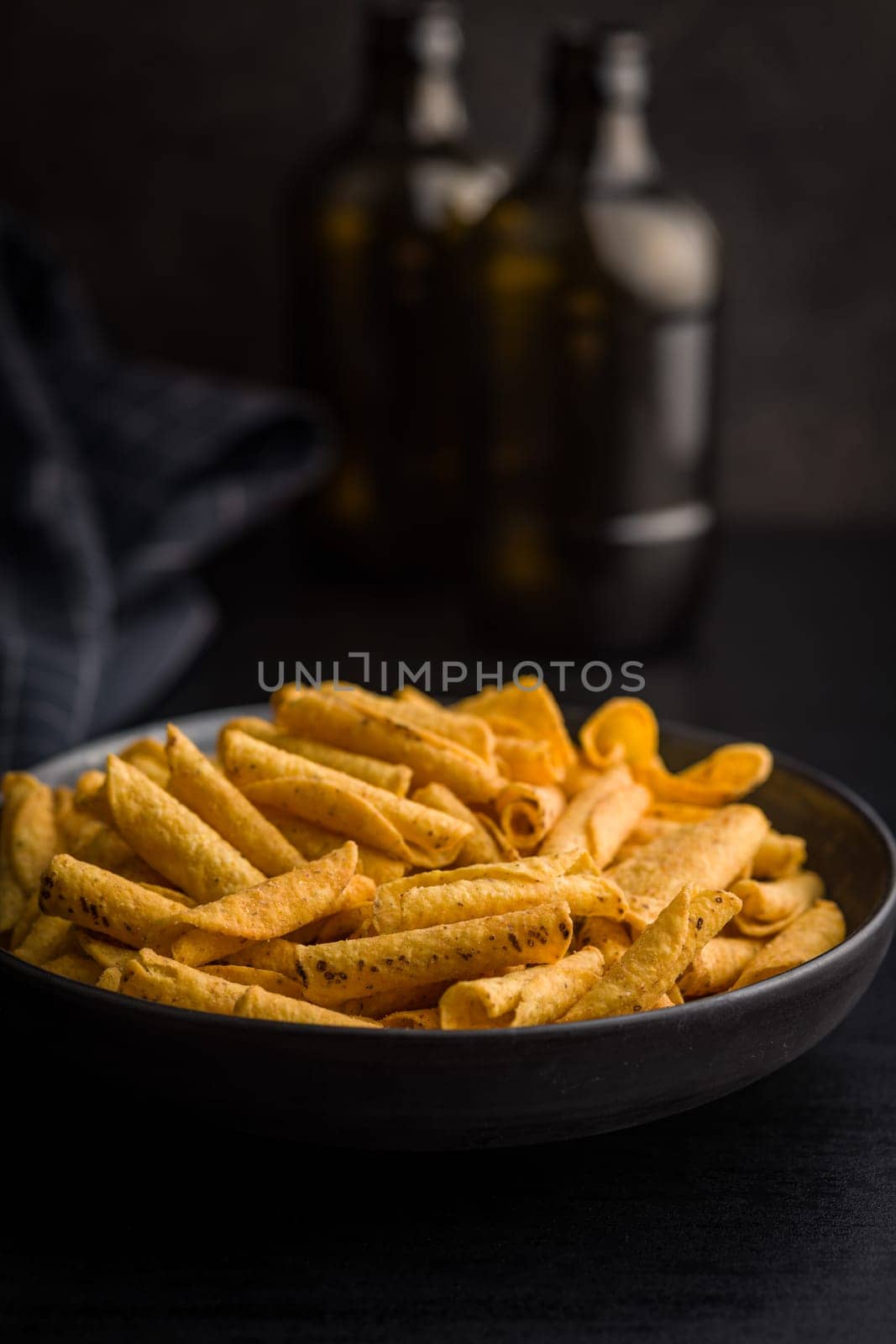 Rolled nachos tortilla chips on plate on a black table.