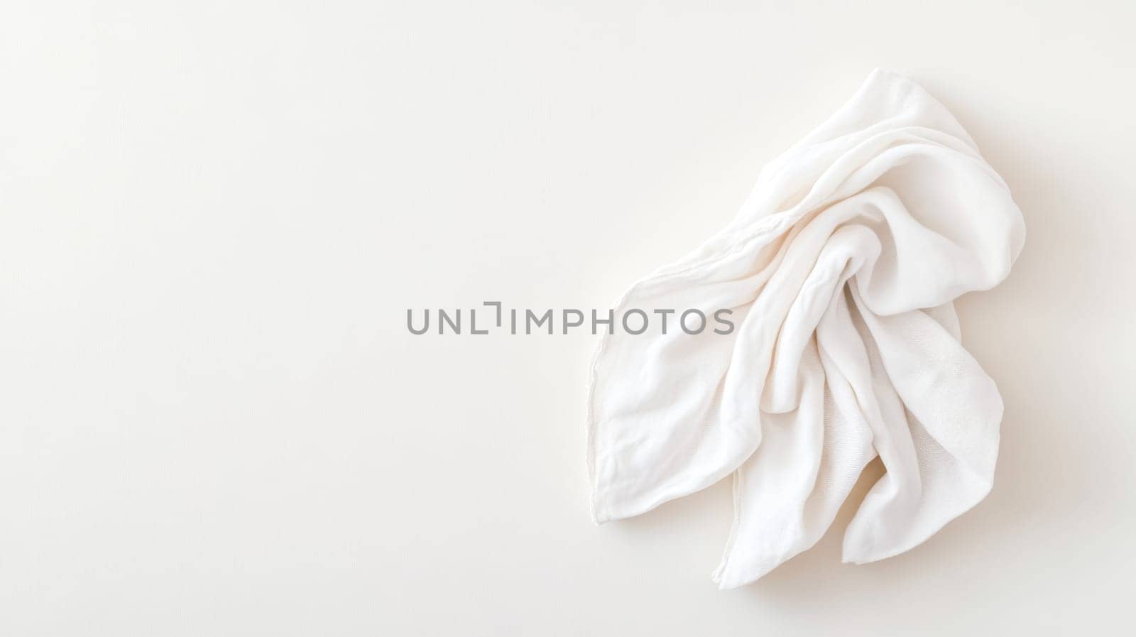 White cloth napkin is elegantly folded on a neutral background, creating a minimalist and stylish composition with ample copy space for text or design elements