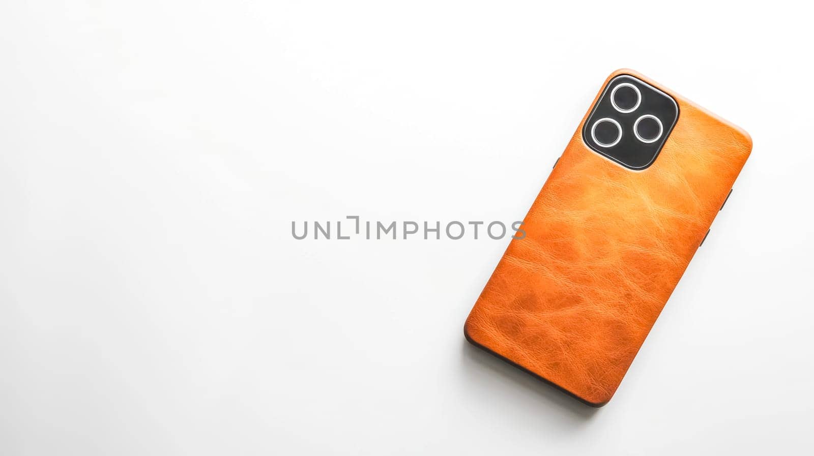Contemporary mobile phone resting in an elegant brown leather case on a pristine white surface, highlighting a perfect blend of style and protection for modern communication needs