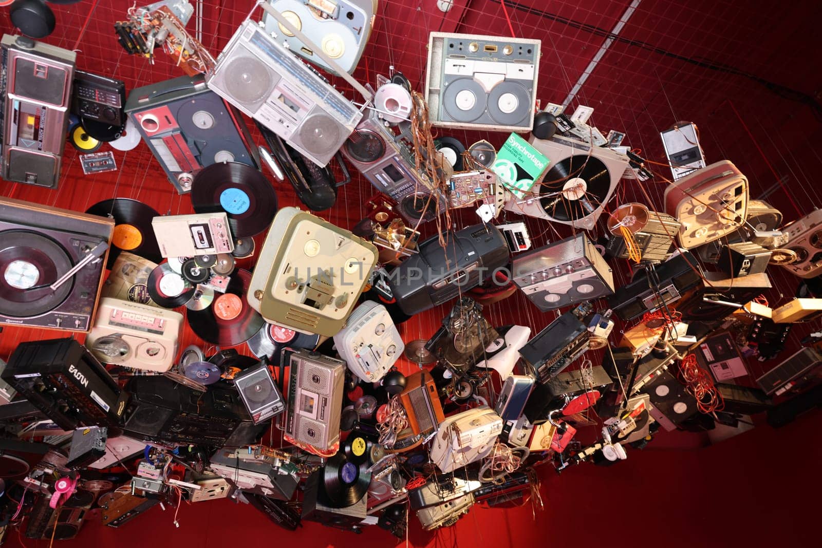 Venice, Italy - May 7 2024: Foreigners Everywhere 60th Venice Art Biennale. John Akomfrah, Listening All Night To The Rain at British Pavilion. Old video and audio players hanging from the ceiling of the red room.