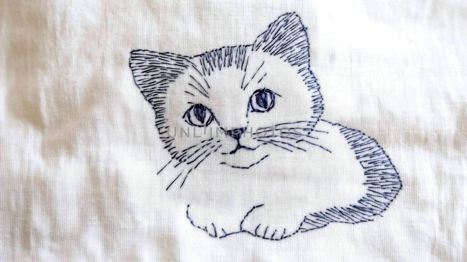 Simple line stitch embroidery featuring a cat resting on soft white fabric, highlighting a minimalist design and showcasing delicate needlework with intricate details