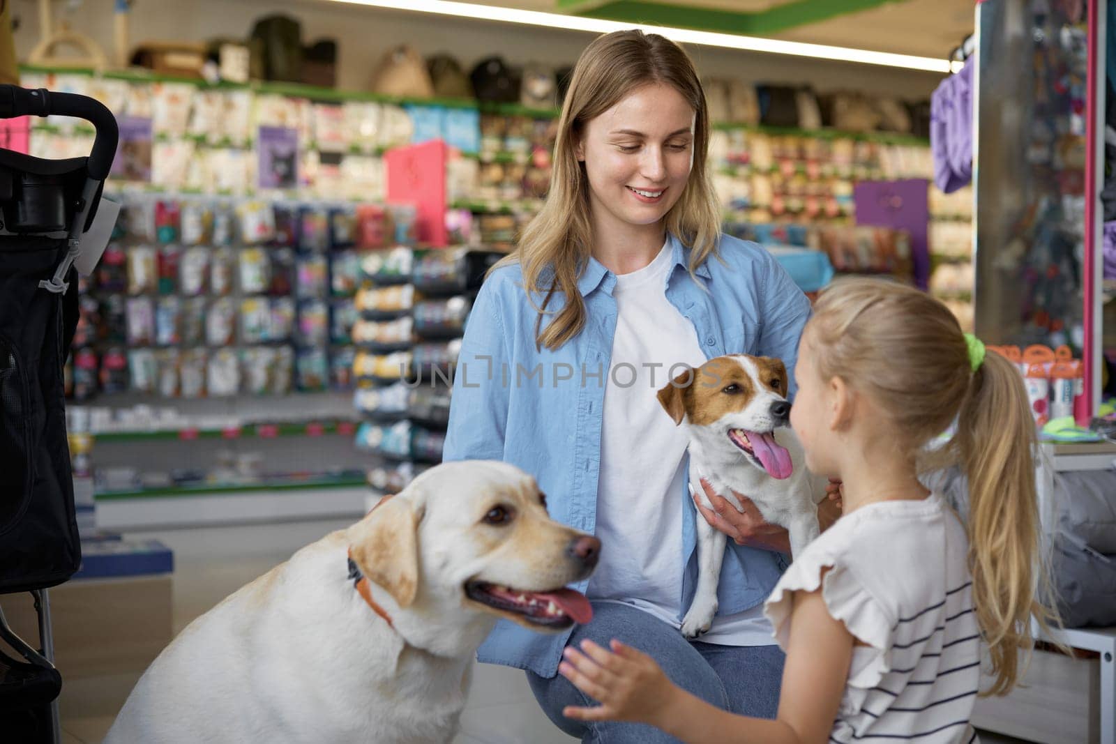Happy mother and daughter choosing between small and big dog at vet shop. Buying new pet for home