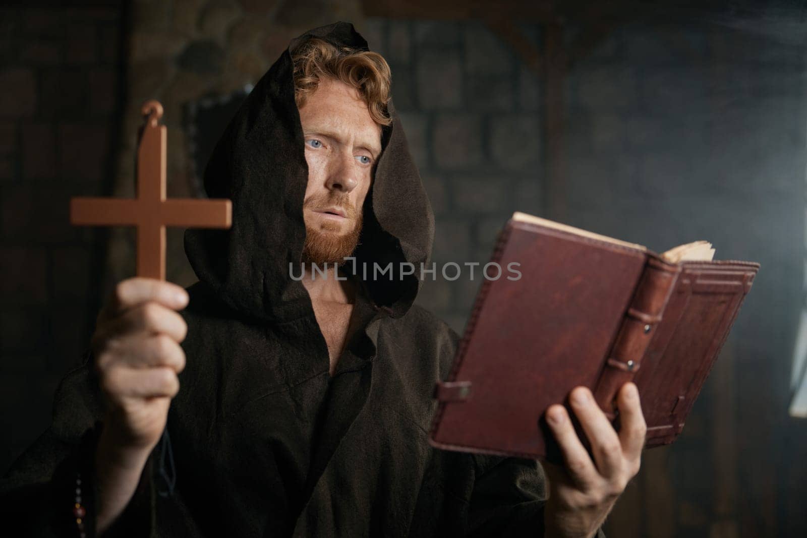 Priest holding cross and holy bible reading prayer and performing exorcism rite selective focus