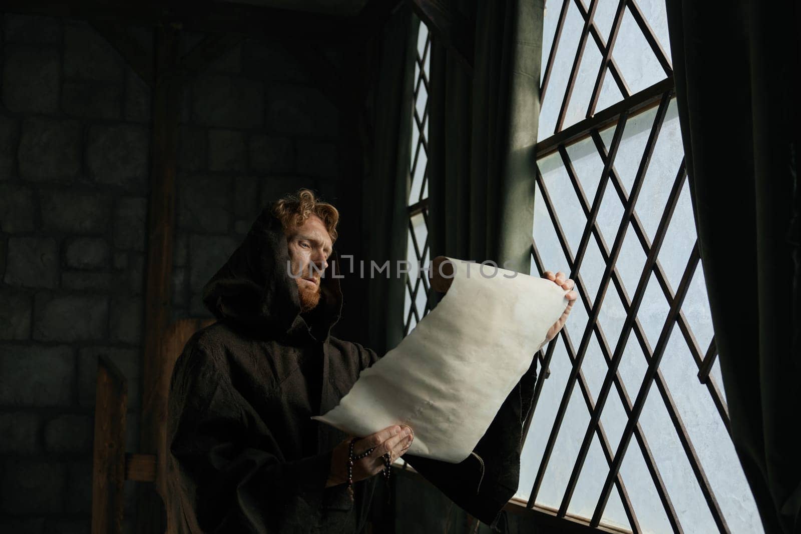 Medieval monk reading obsolete historical parchments and holy manuscripts. Abbey chronicler preparing monastic archive