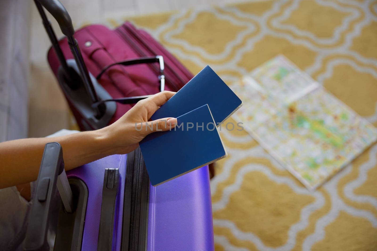 Closeup cropped shot of female hand holding passports for romantic travel for two over suitcases luggage