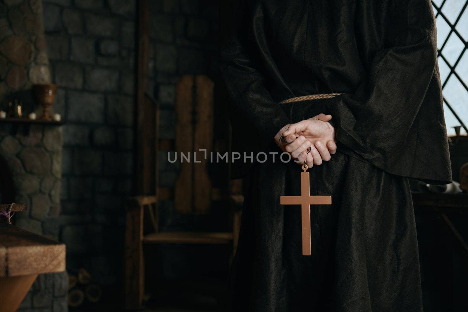 Closeup view cropped shot with golden cross in priest monk hands. Medieval friar praying concept