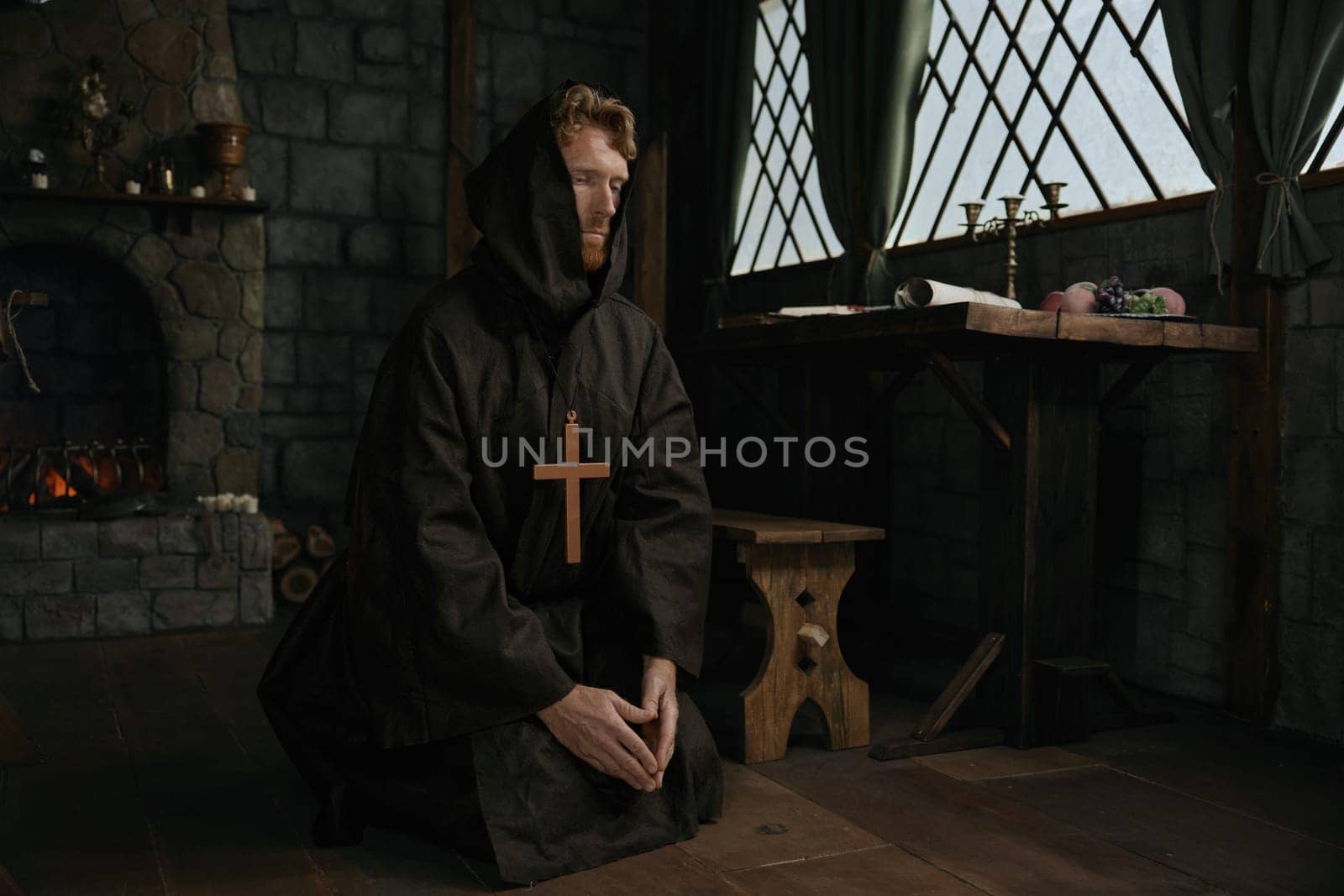 Monk wearing robe wishing and praying to God looking upward in mediaeval monastery