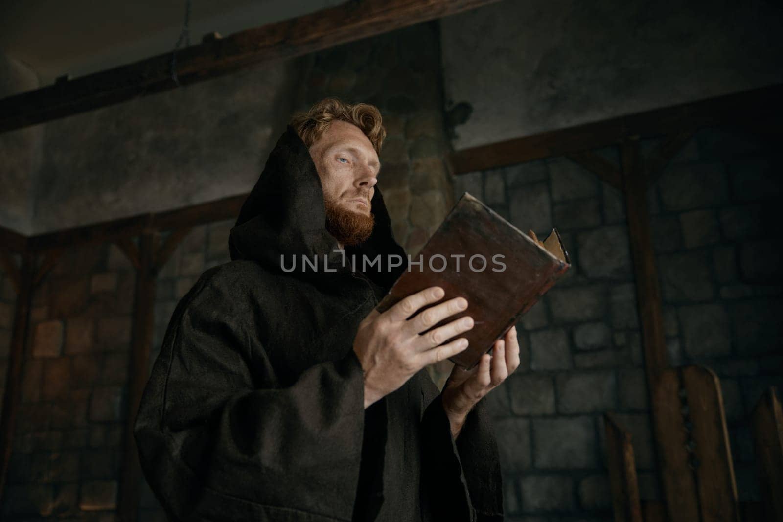 Thoughtful medieval monk reading ancient book or antique manuscripts in cathedral. Religion and faith concept