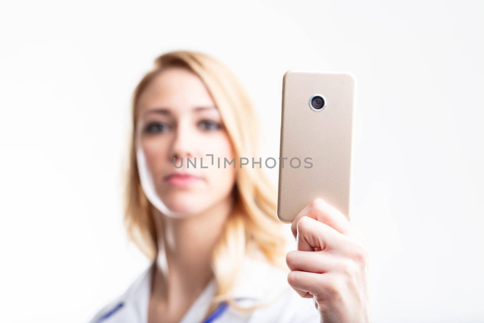In-focus smartphone, held by a blurry blonde medic, highlights the utility of telemedicine and healthcare mobile apps
