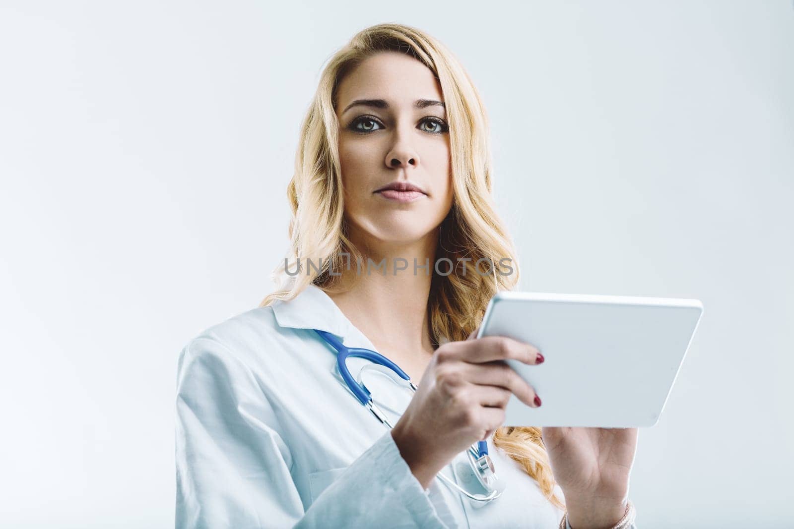 Confident doctor wearing a lab coat and stethoscope is holding a digital tablet, exploring the potential of artificial intelligence and its impact on healthcare