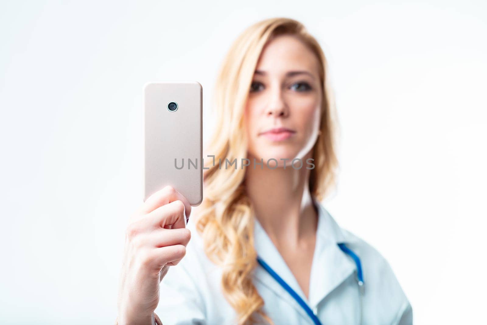Young female doctor blurred behind an in-focus smartphone, reminding of the usefulness of telehealth and medical apps