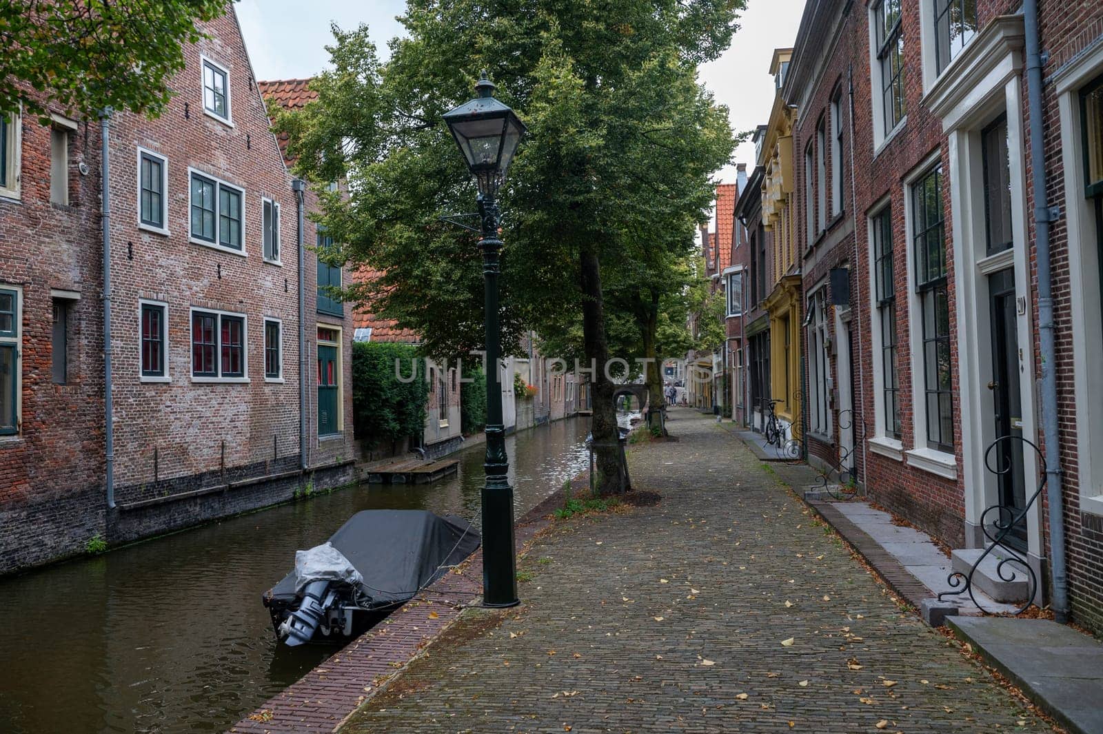 Houses on a water canal, a small street and with boats in the old town of Alkmaar in the Netherlands
