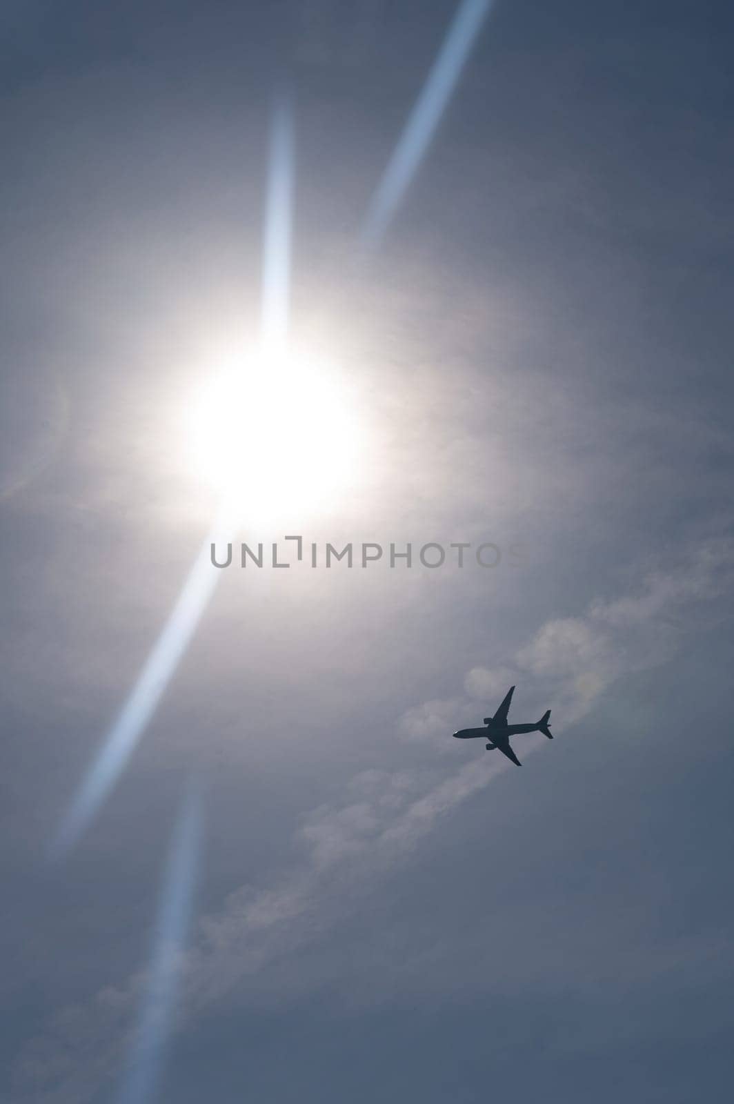 An airplane from below with lots of sky and bright sun,An airplane from below with lots of sky and bright sun
