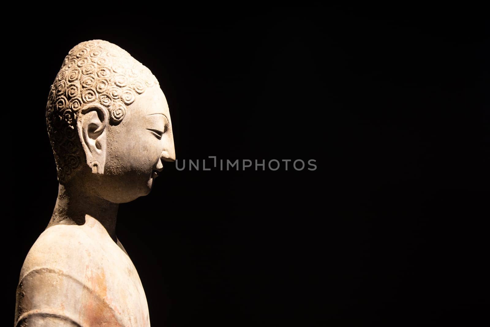 Turin, Italy - 28 December 2023: Oriental Art Museum, Standing Buddha, Northern China, late 6th c.. Copy space, black background