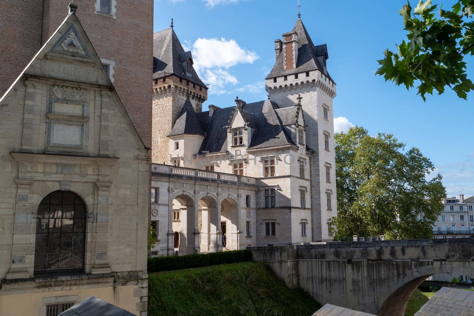 A large building with a tower and a small building in the background. The large building has a lot of windows and a balcony, Pau, France