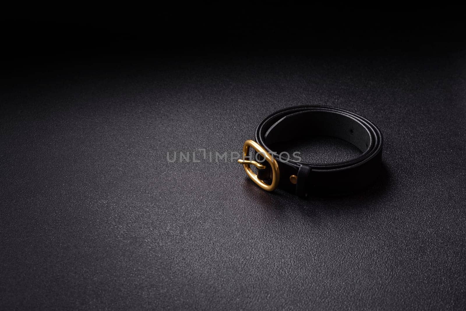 New leather women's belt with an old-style metal buckle on a dark concrete background
