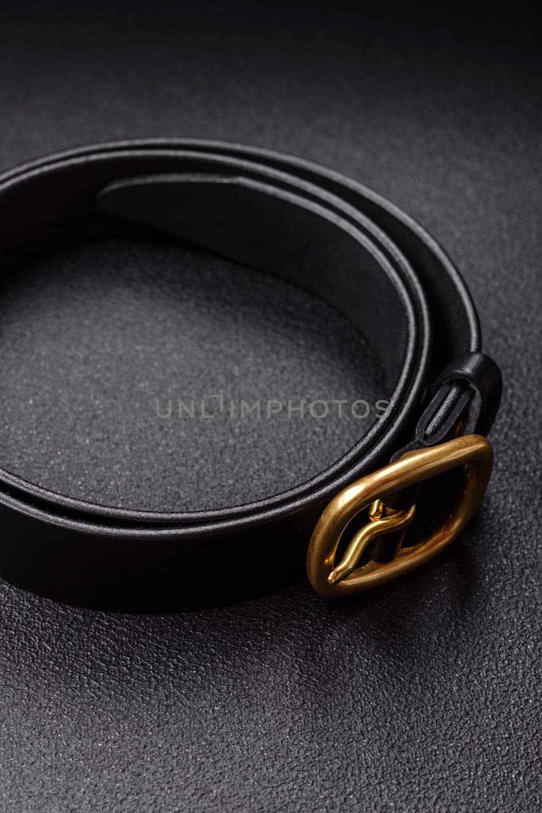 New leather women's belt with an old-style metal buckle on a dark concrete background
