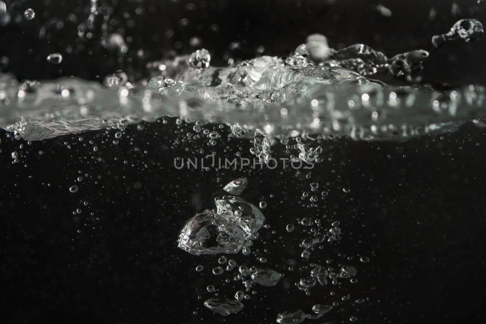 Water splashing as it's poured into aquarium tank, black background