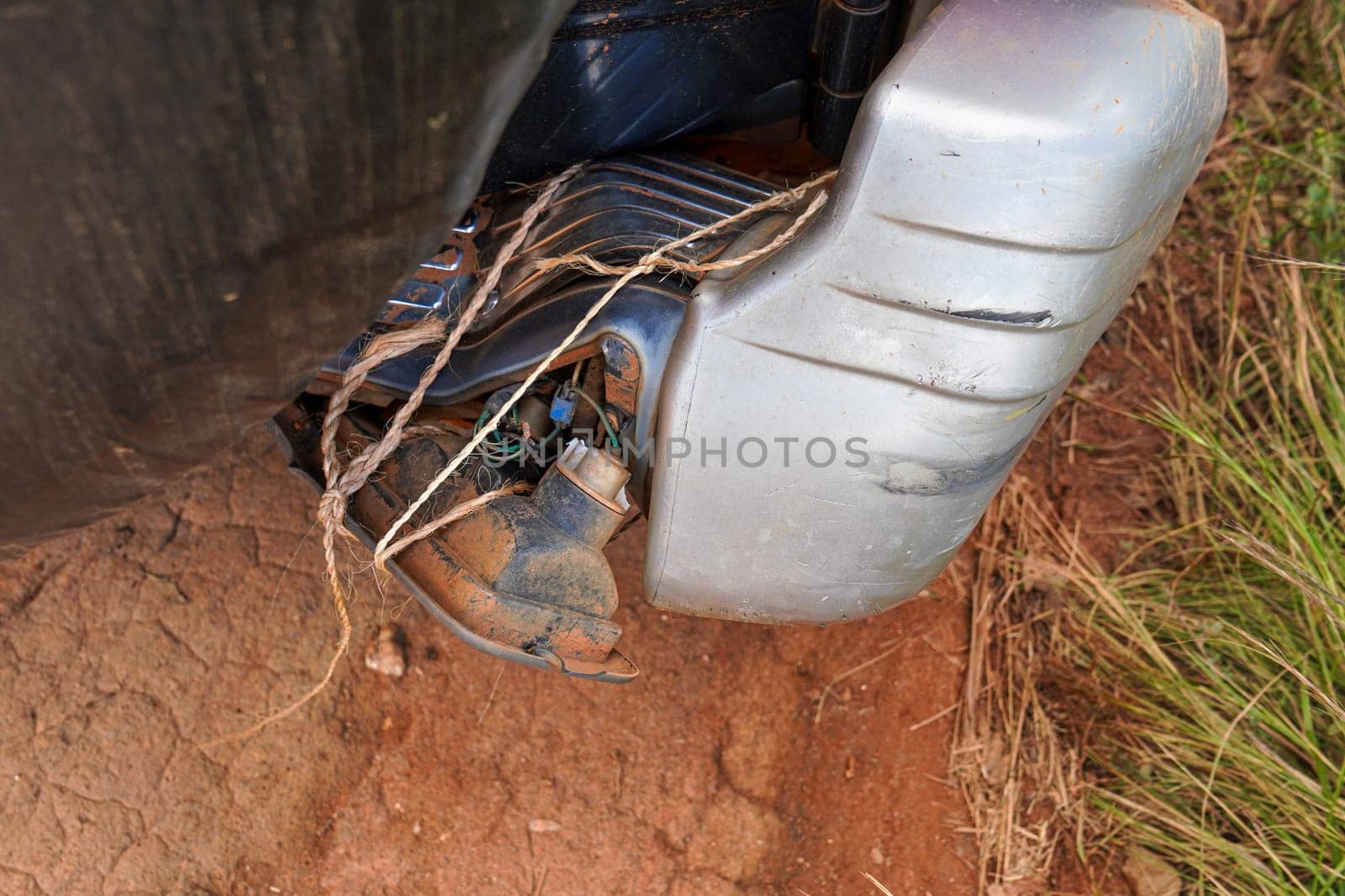Broken tail light, dirty from red dust, of 4x4 off road vehicle, fixed provisionally only with thin rope.