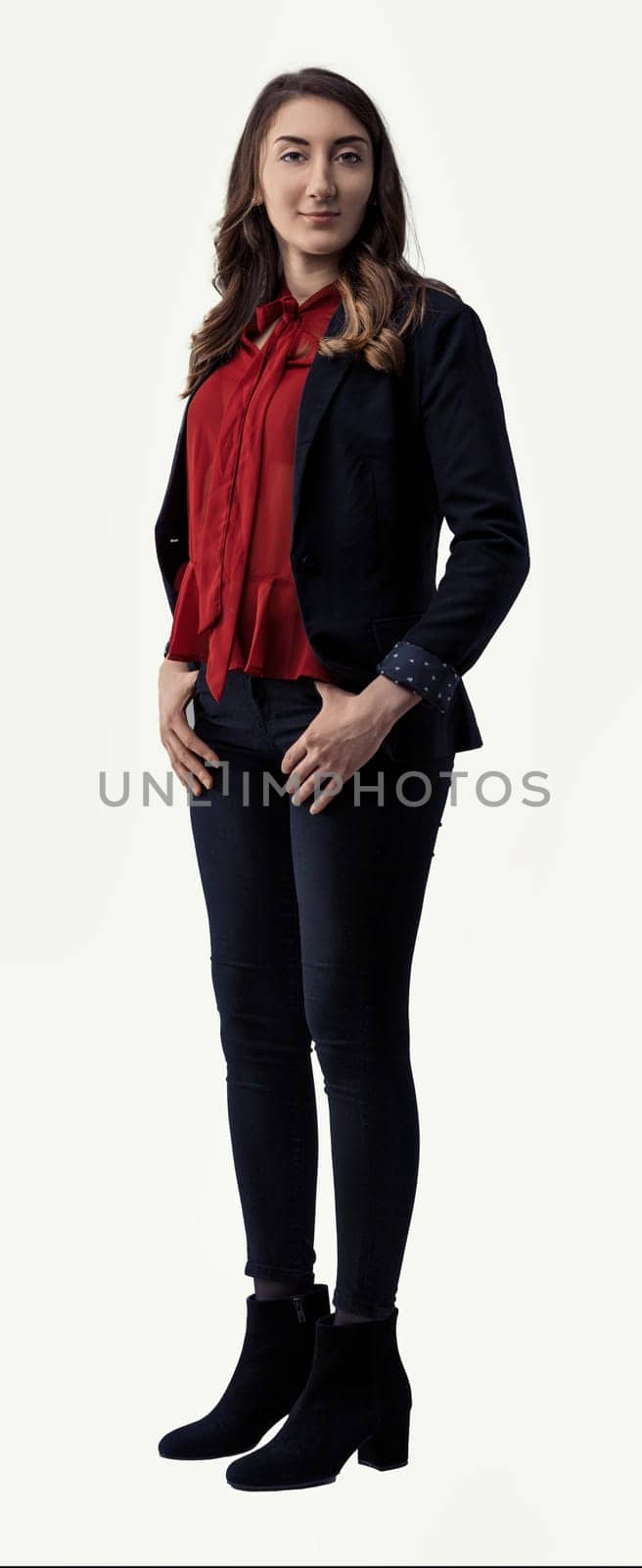 Full-body portrait of a confident young businesswoman standing with her hands on her hips, exuding professionalism and determination against a clean white background