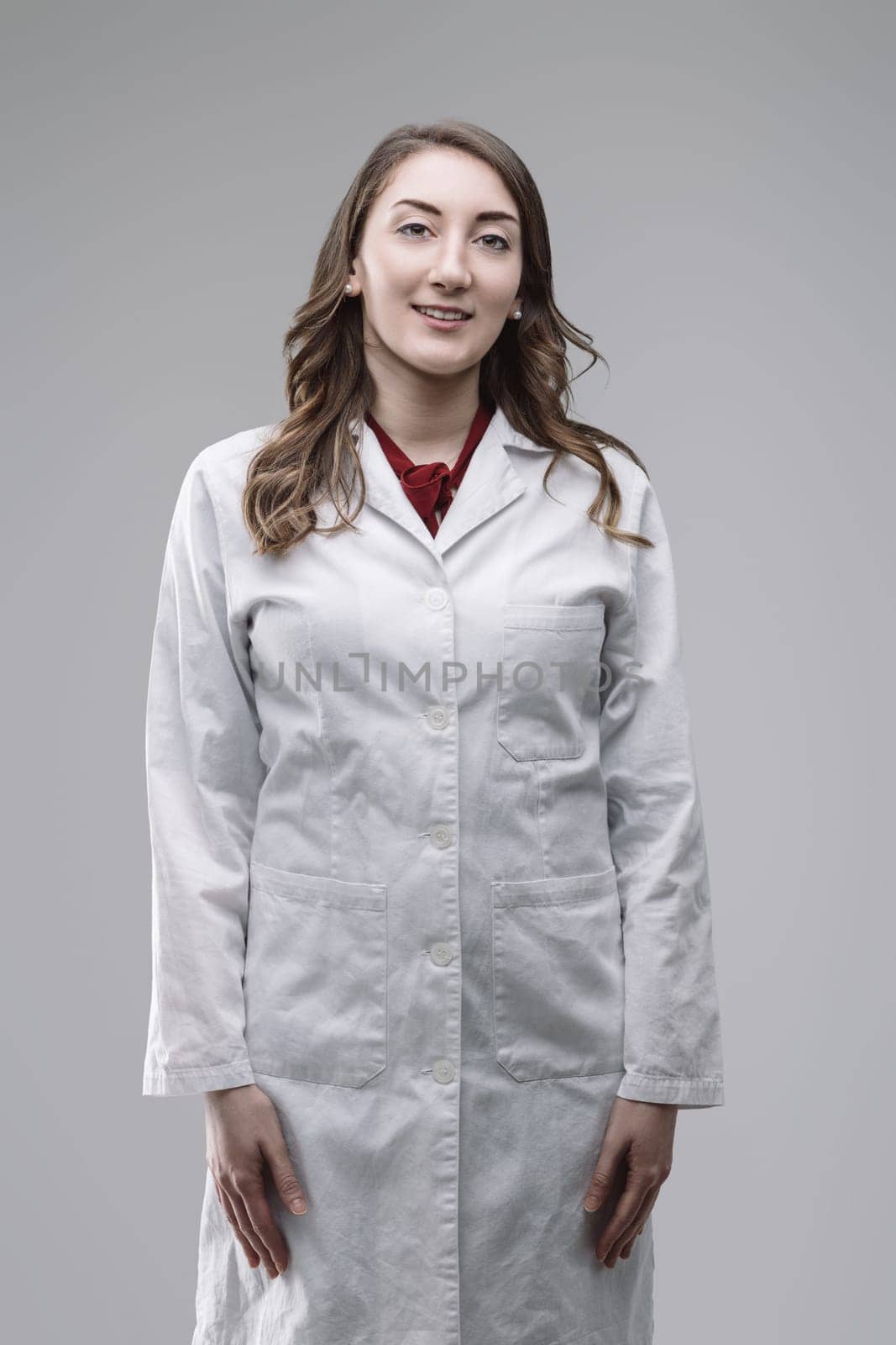 Portrait of a confident young female scientist smiling at the camera while wearing a lab coat, showcasing her expertise and passion for scientific research