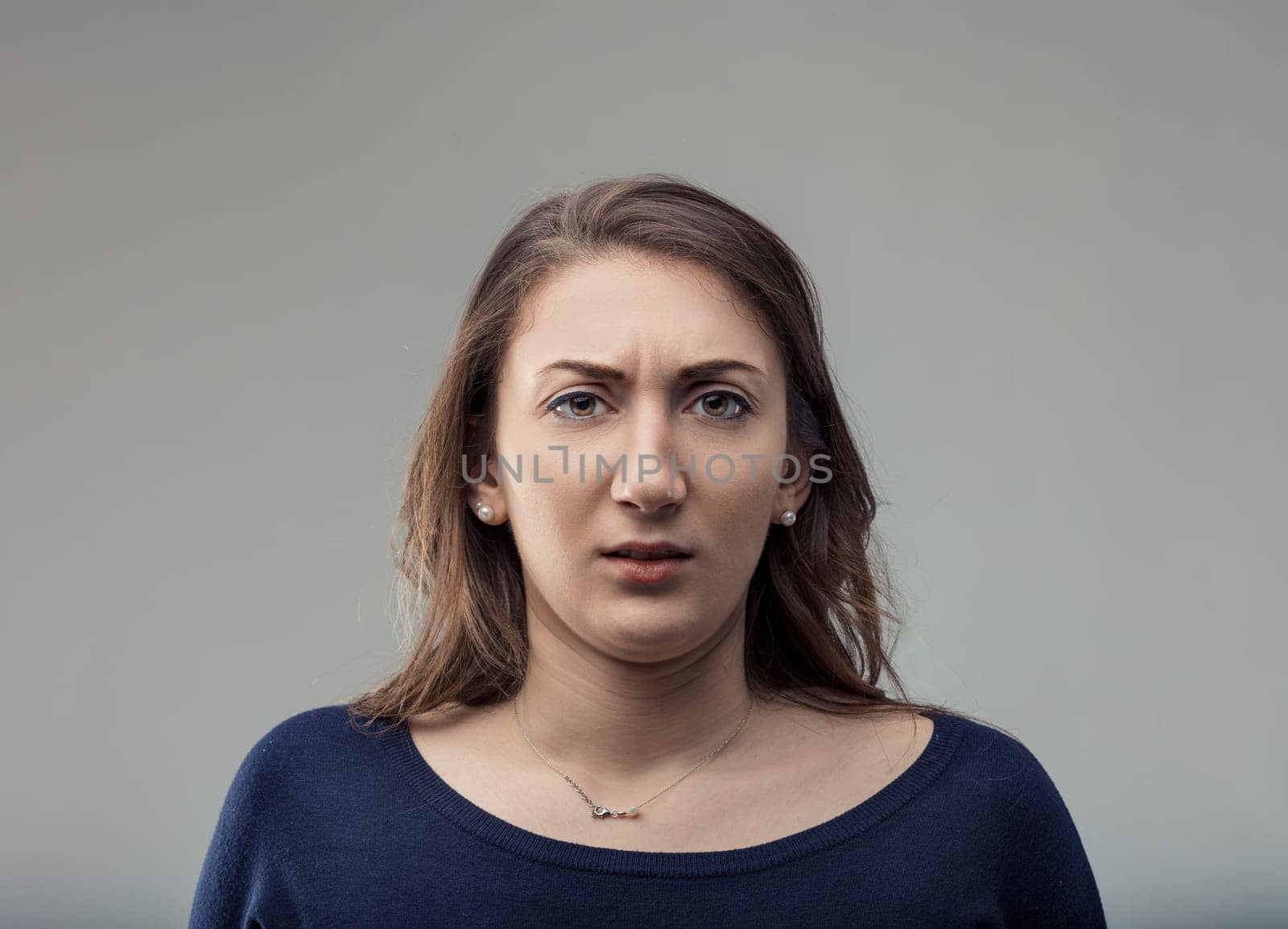 Portrait featuring a disgusted young adult woman with brown hair and brown eyes, gazing at the camera with a displeased and skeptical expression on her face