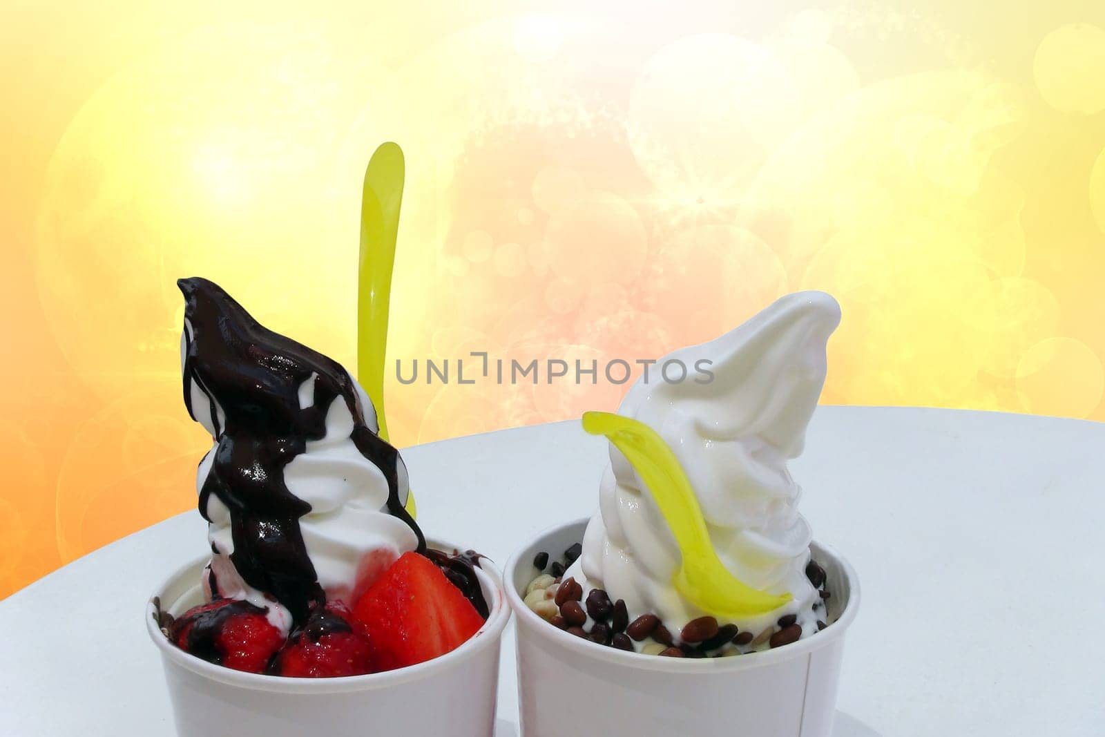 Fresh ice cream. Delicious sundae with vanilla and peach ice cream and chocolate sauce and various fruits on the table over abstract background. Dessert with copy space.