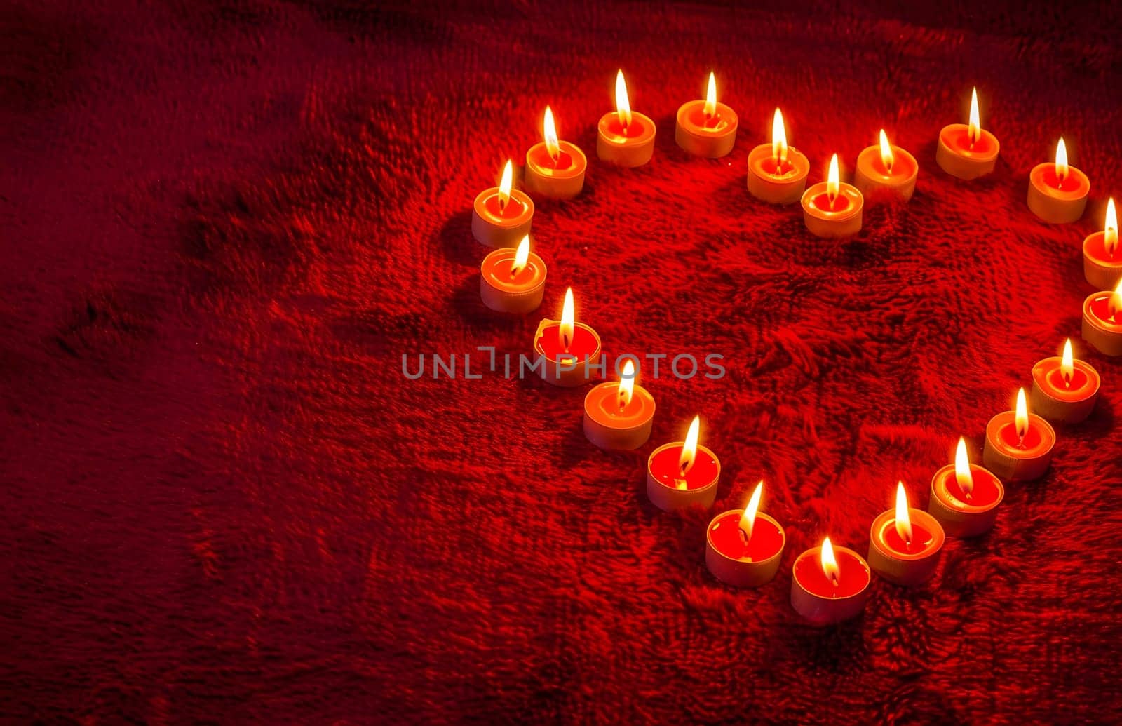 Heart-shaped candles arrangement on red background. Romantic and warm. Perfect for Valentine's Day.