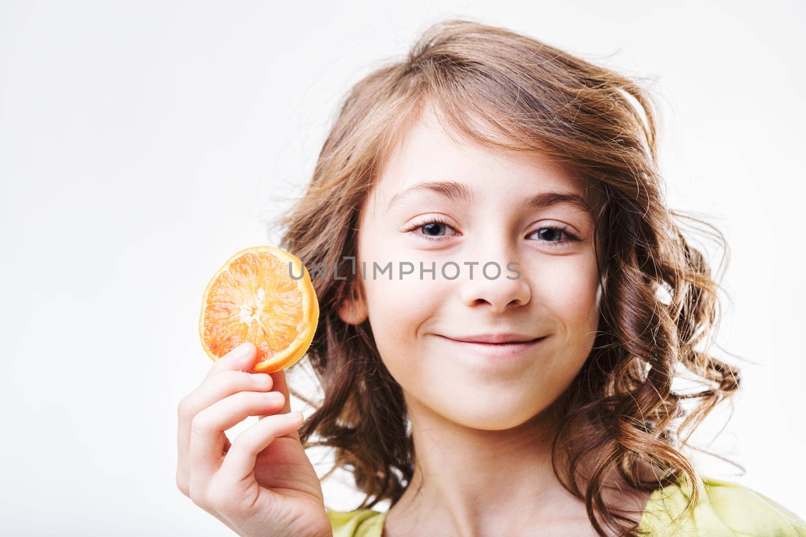 Cheerful young girl holding a vibrant slice of orange, embodying the joy of healthy eating and nutrition for children. Celebrating freshness and wellness through nutritious choices