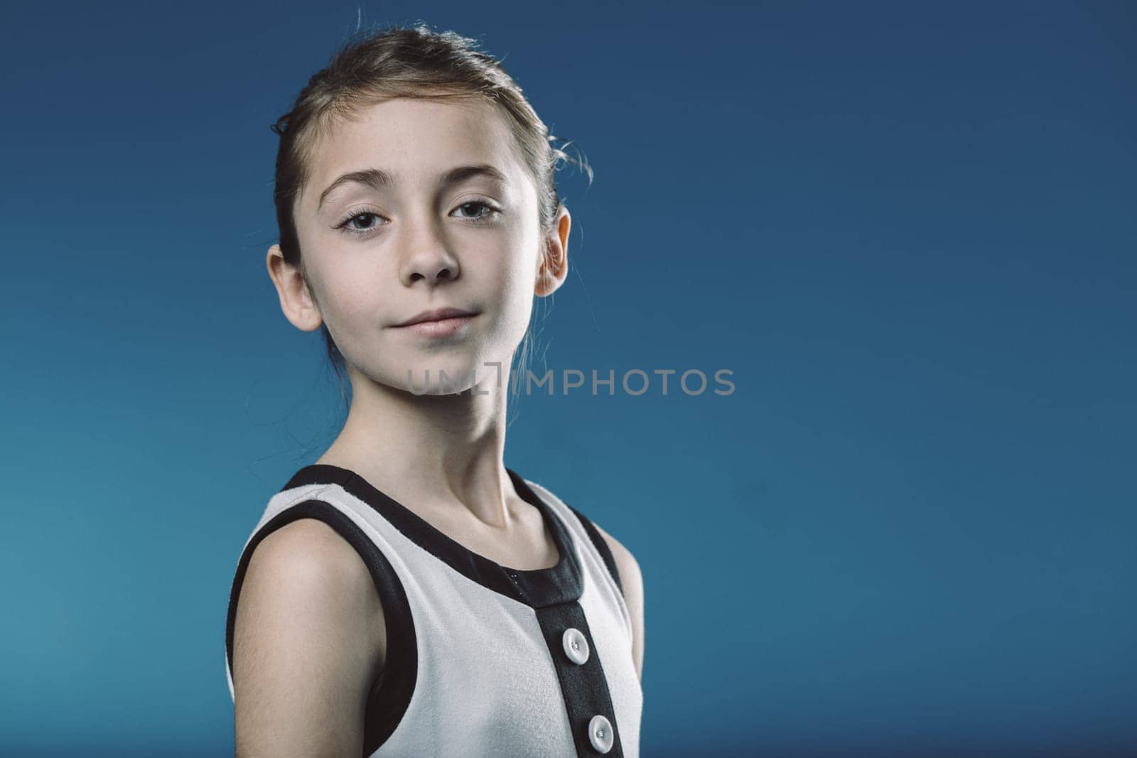 Young girl exuding confidence against a blue background, showcasing poise and maturity, capturing the essence of youth and limitless potential