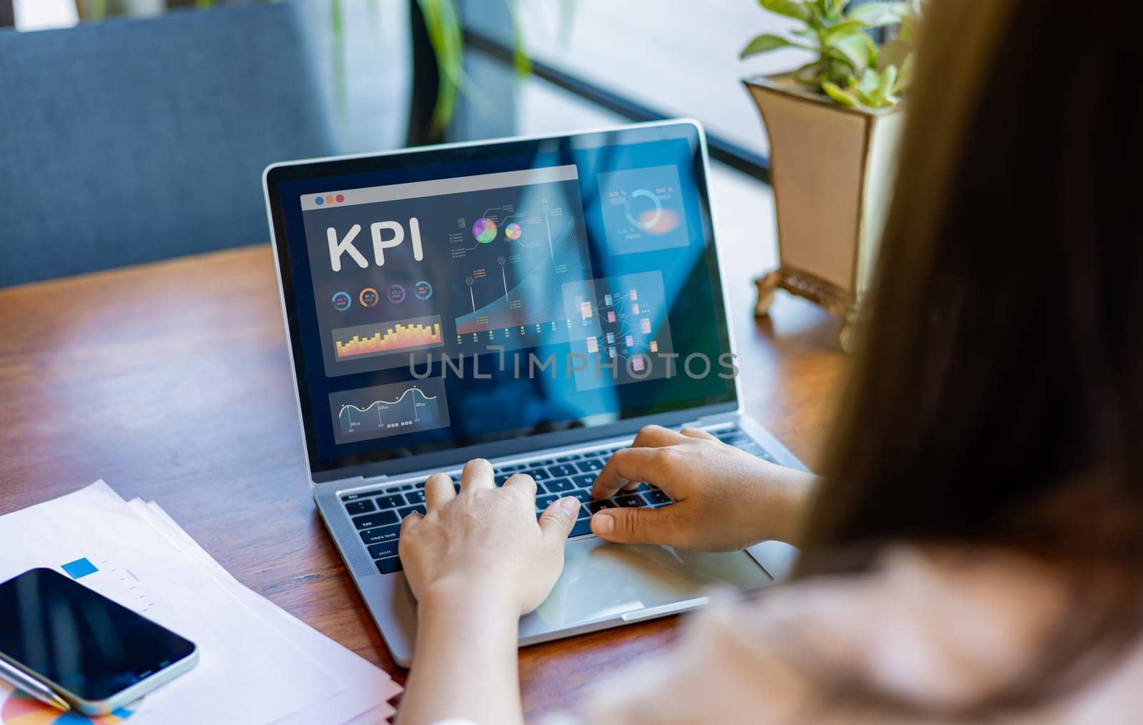 Businesswoman analyst utilizes a computer and a dashboard for business data analysis and a data management system with KPI. The concepts of technology, finance, operations, sales, and marketing.