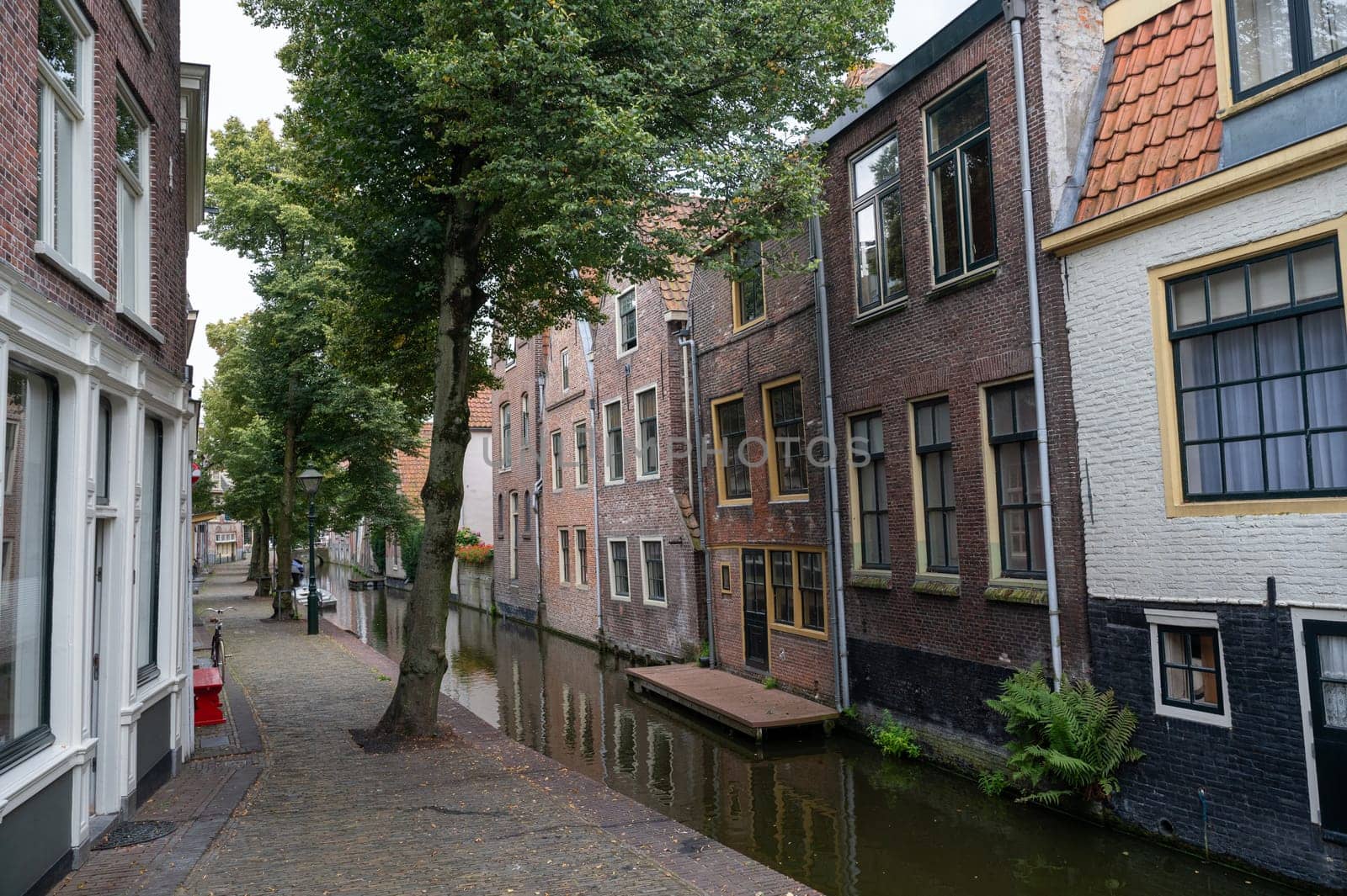 Houses on a water canal, a small street and with boats in the old town of Alkmaar in the Netherlands