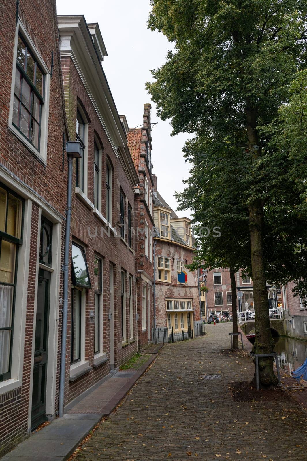 Houses on a water canal, a small street and with boats in the old town of Alkmaar in the Netherlands
