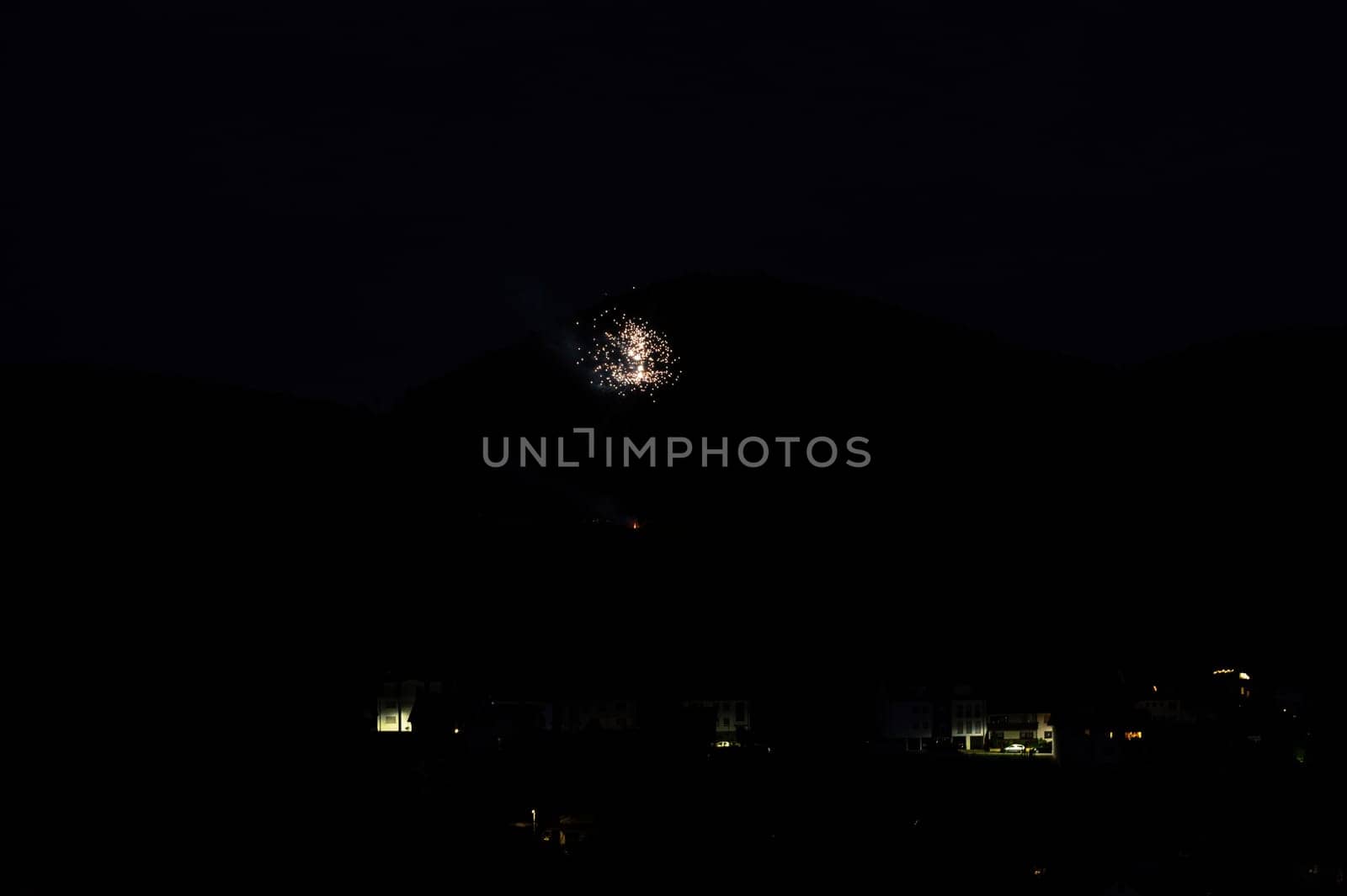 A firework rocket in the sky on a mountain at night, a few illuminated houses in the foreground,A firework rocket in the sky on a mountain at night, a few illuminated houses in the foreground