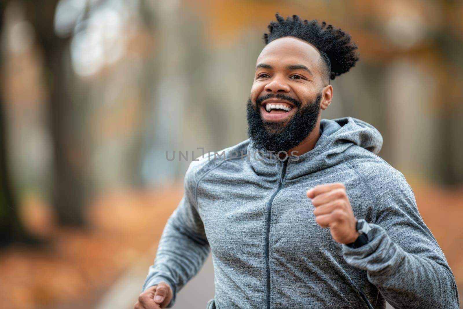A smiling, bearded man with dreadlocks laughs joyfully while wearing sunglasses in an outdoor, natural setting with a blurred background