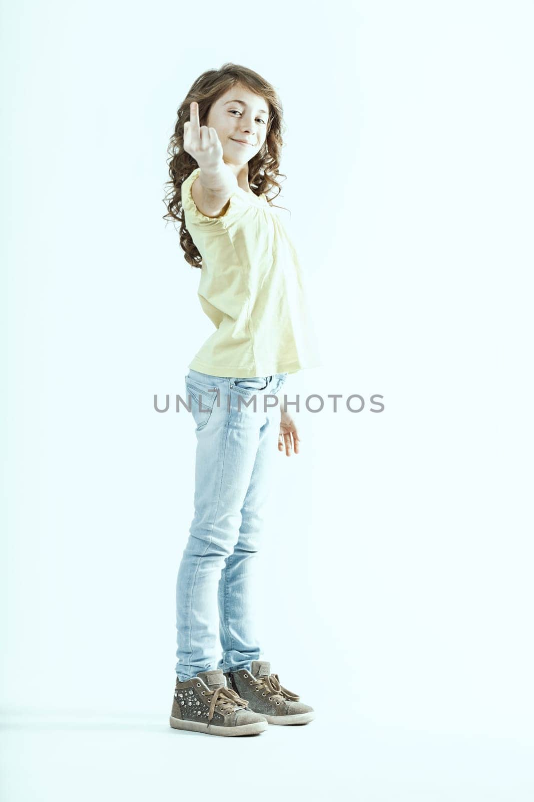 Studio shot featuring a preteen girl making an obscene gesture with her middle finger raised, boldly expressing rebellion and defiance against authority in a striking display of attitude