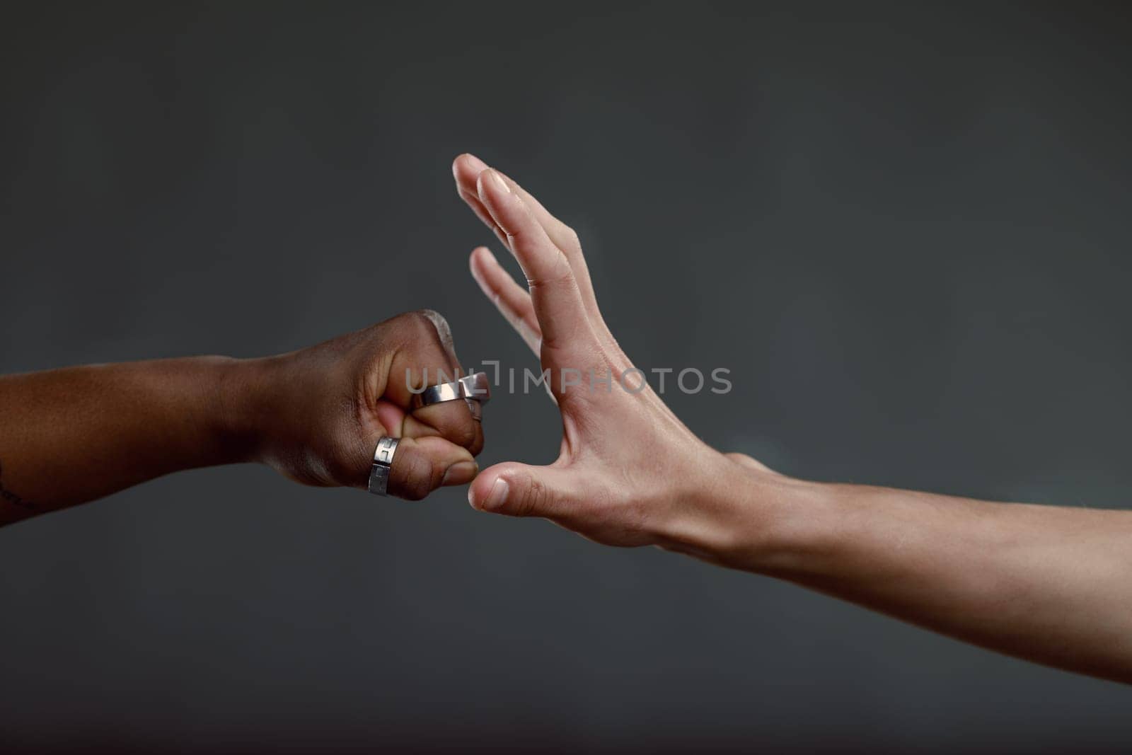 One hand is forming a fist, while the other hand is open, creating a sense of tension and uncertainty about whether a handshake, fist bump, or conflict will ensue