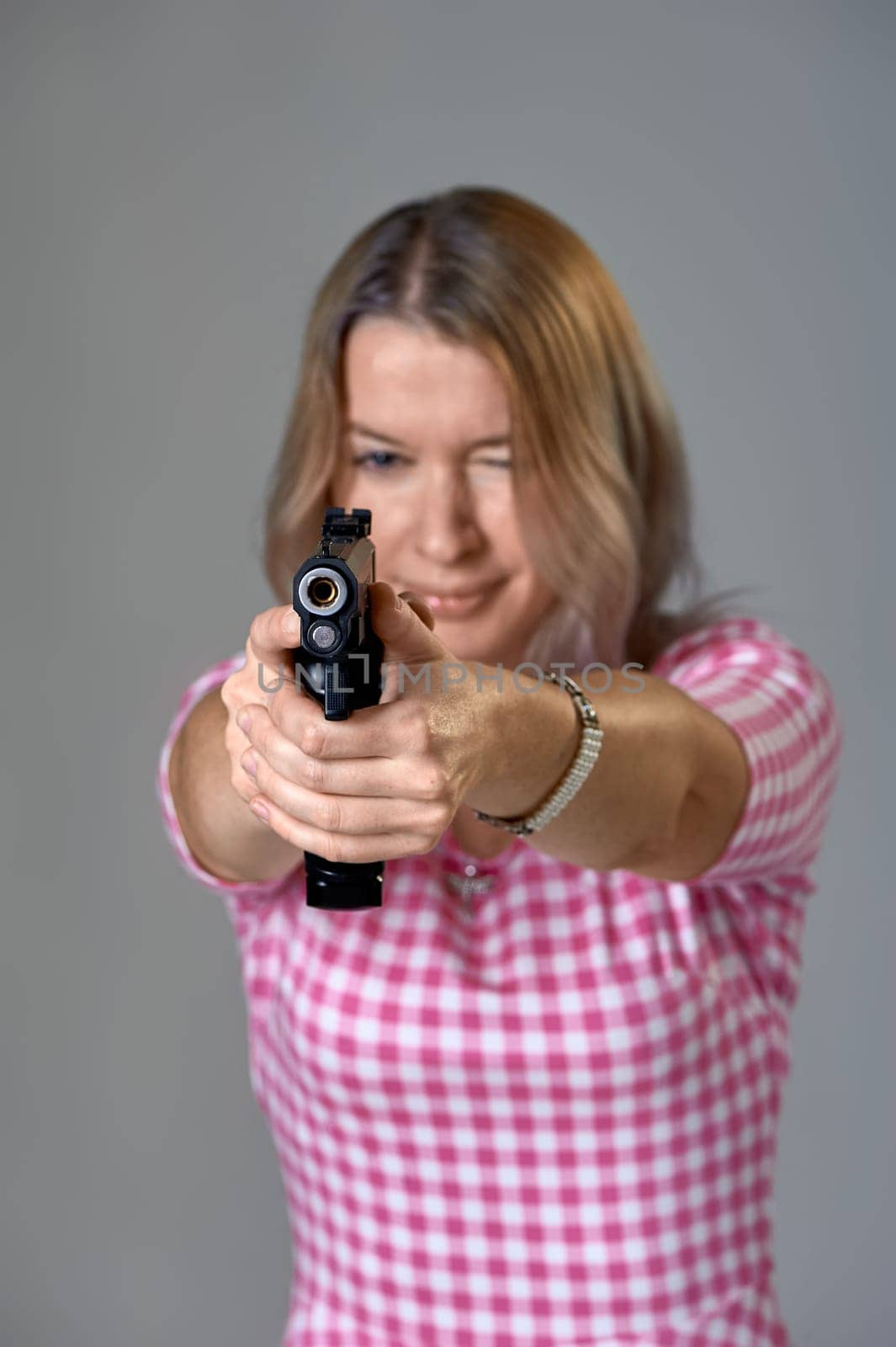 a beautiful woman aims a gun. High quality photo
