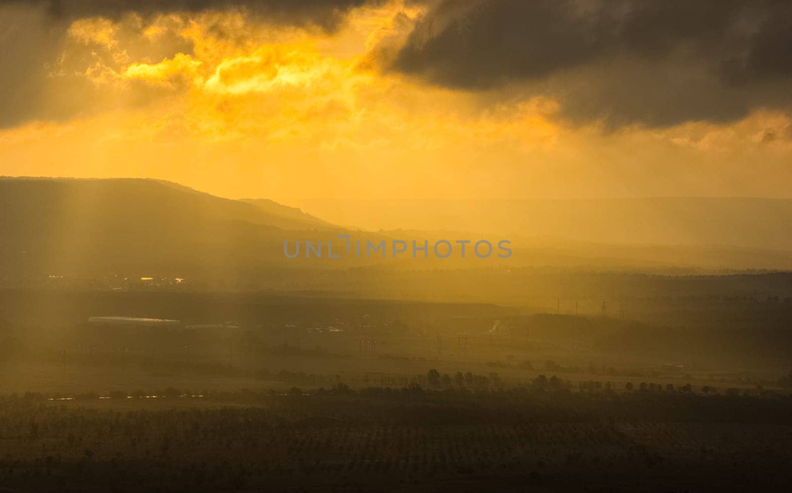 Dawn in the mountains of Crimea. A light haze of mist over the mountains and rays of the sun through the clouds.