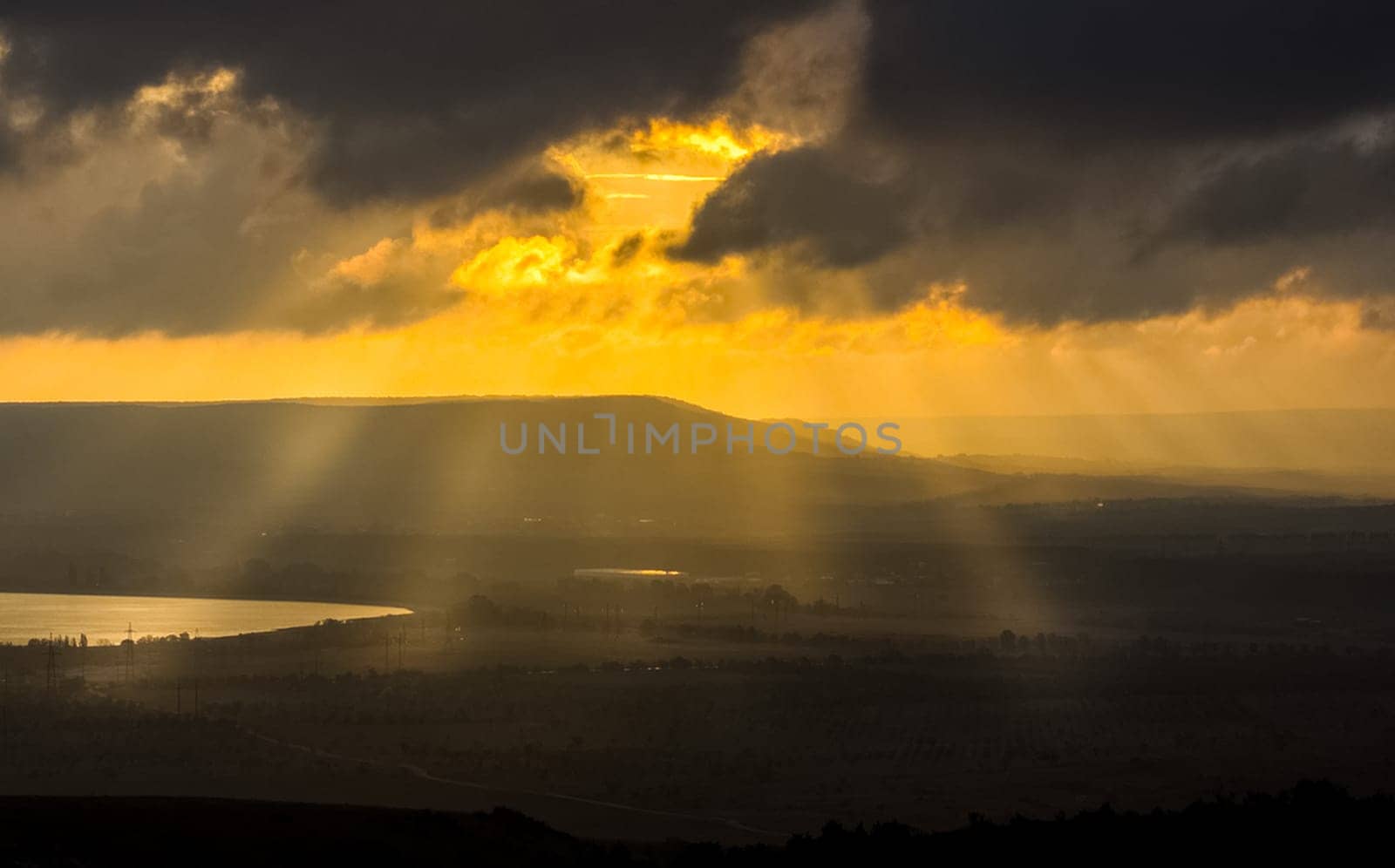 Dawn in the mountains of Crimea. A light haze of mist over the mountains and rays of the sun through the clouds.