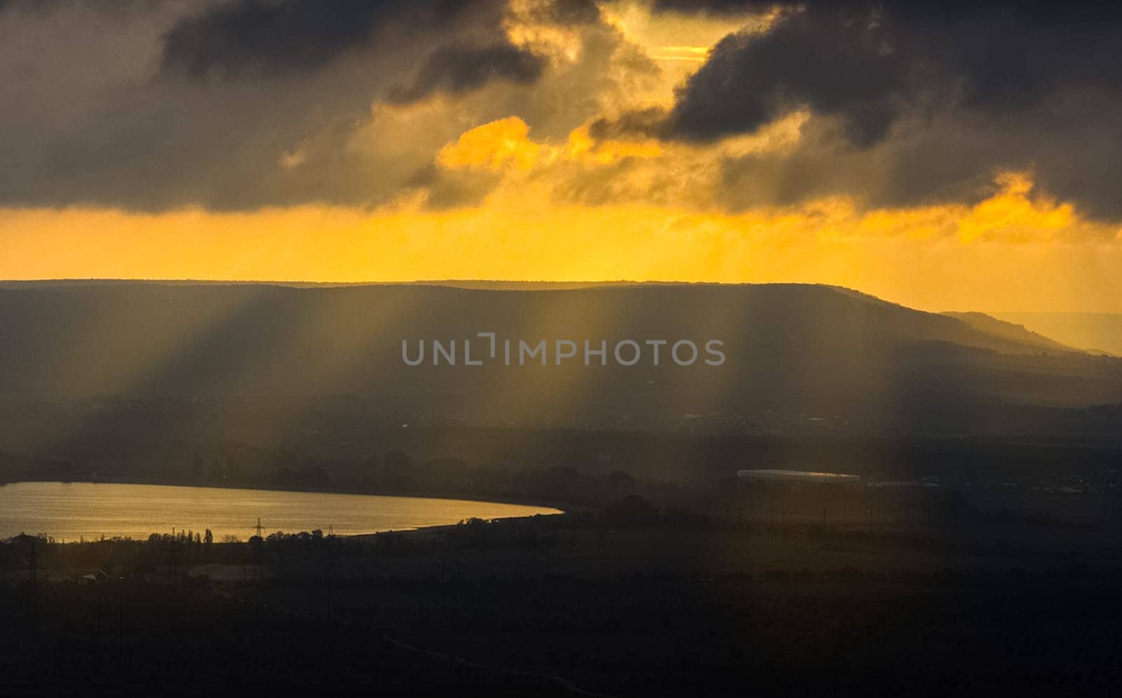 Dawn in the mountains of Crimea. A light haze of mist over the mountains and rays of the sun through the clouds.