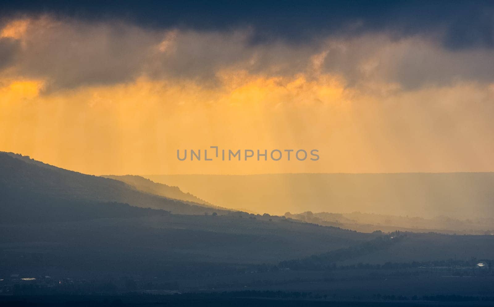 Dawn in the mountains of Crimea. A light haze of mist over the mountains and rays of the sun through the clouds.
