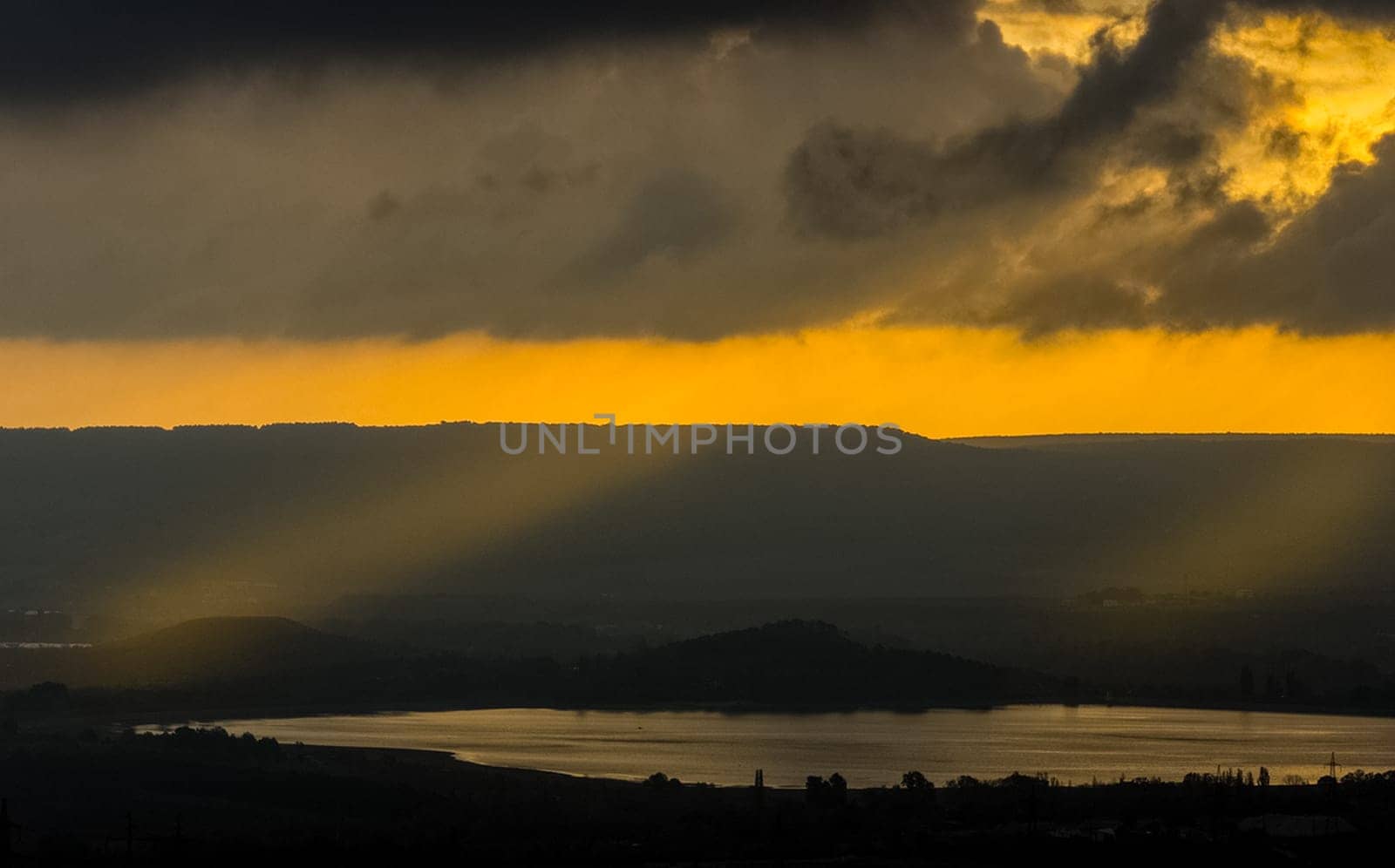 Dawn in the mountains of Crimea. A light haze of mist over the mountains and rays of the sun through the clouds.