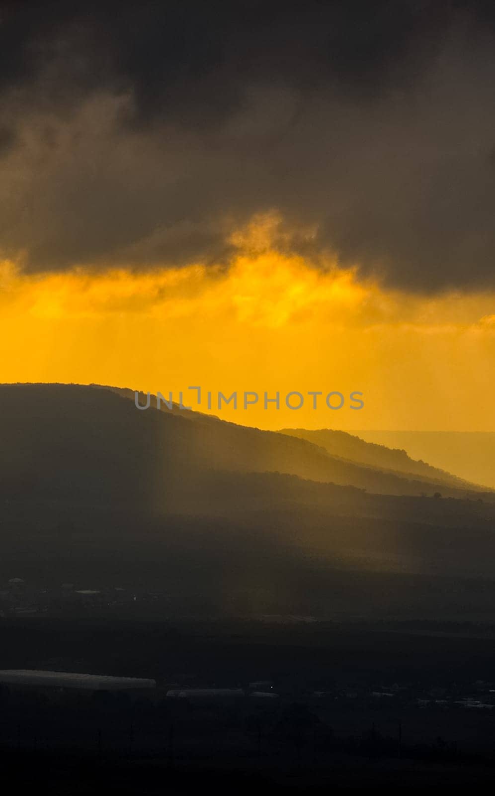 Dawn in the mountains of Crimea. A light haze of mist over the mountains and rays of the sun through the clouds.