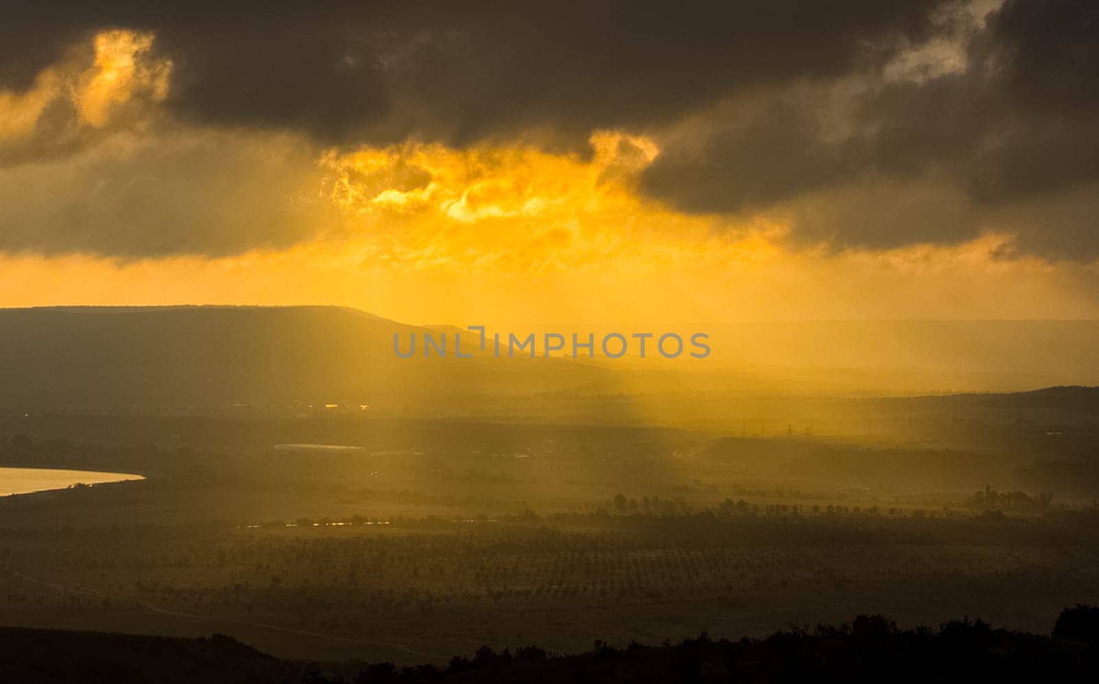 Dawn in the mountains of Crimea. A light haze of mist over the mountains and rays of the sun through the clouds.