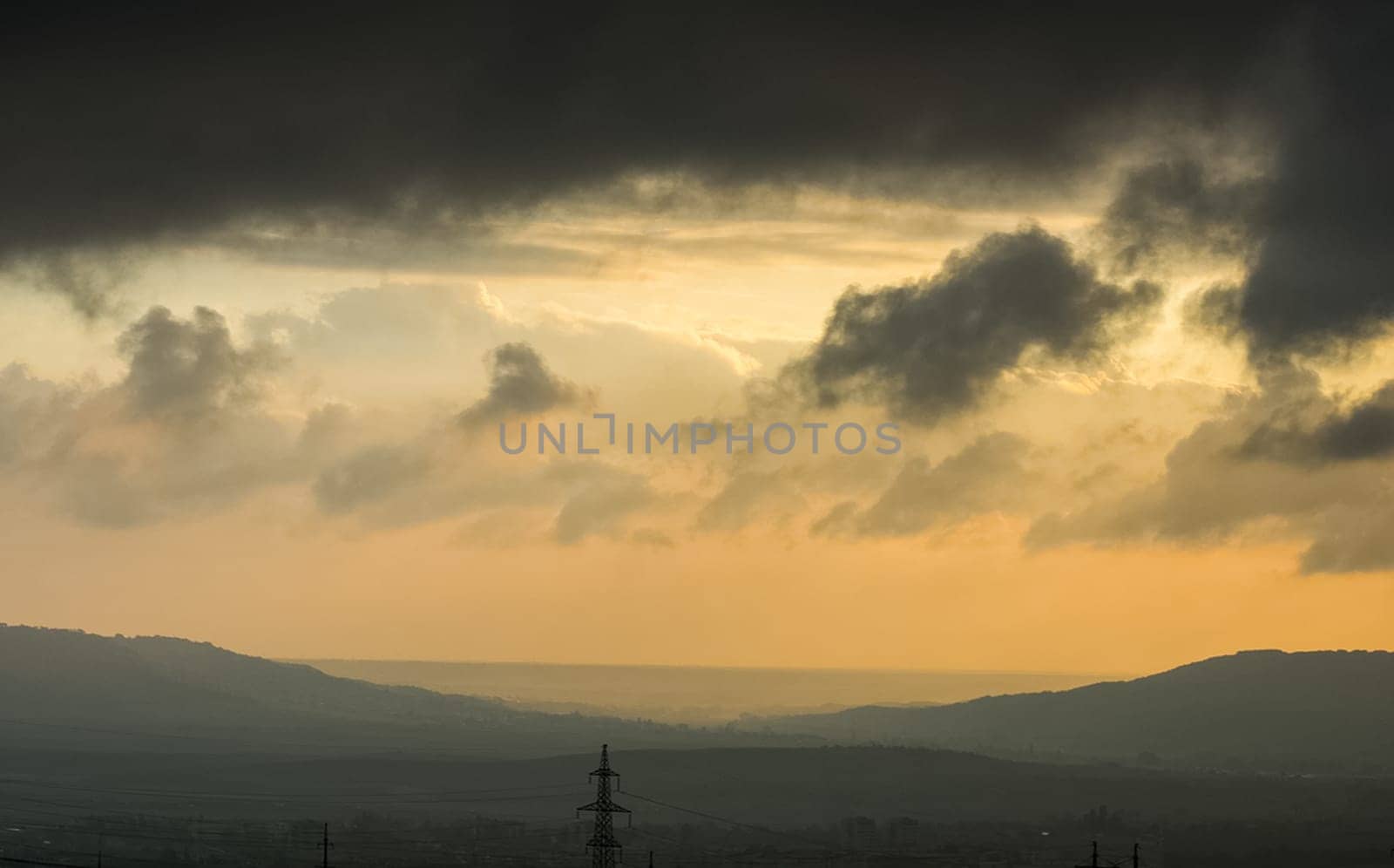 Dawn in the mountains of Crimea. A light haze of mist over the mountains and rays of the sun through the clouds.