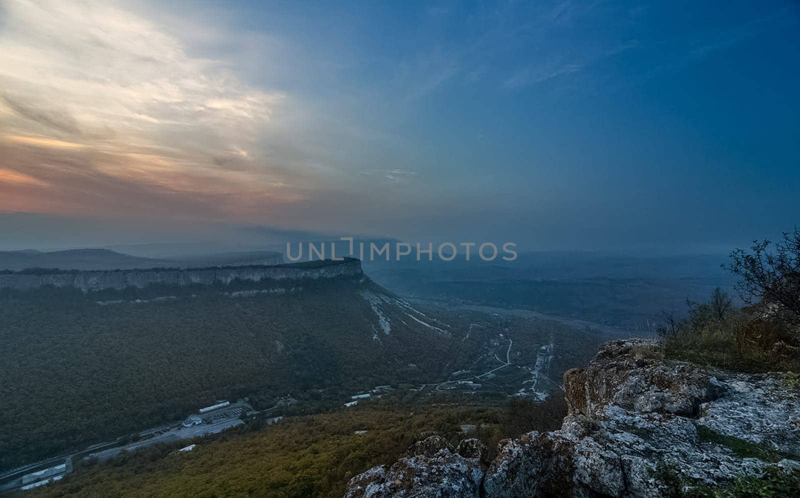 Dawn in the mountains of Crimea. A light haze of mist over the mountains and rays of the sun through the clouds.