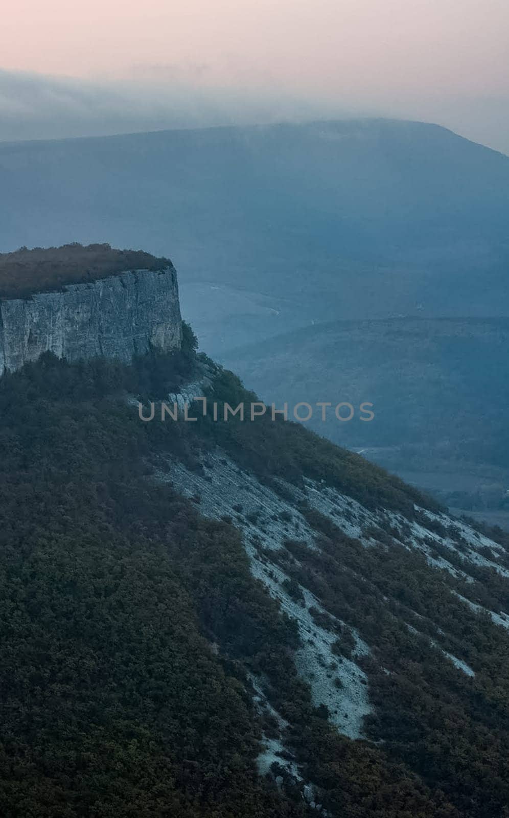 Dawn in the mountains of Crimea. A light haze of mist over the mountains and rays of the sun through the clouds.
