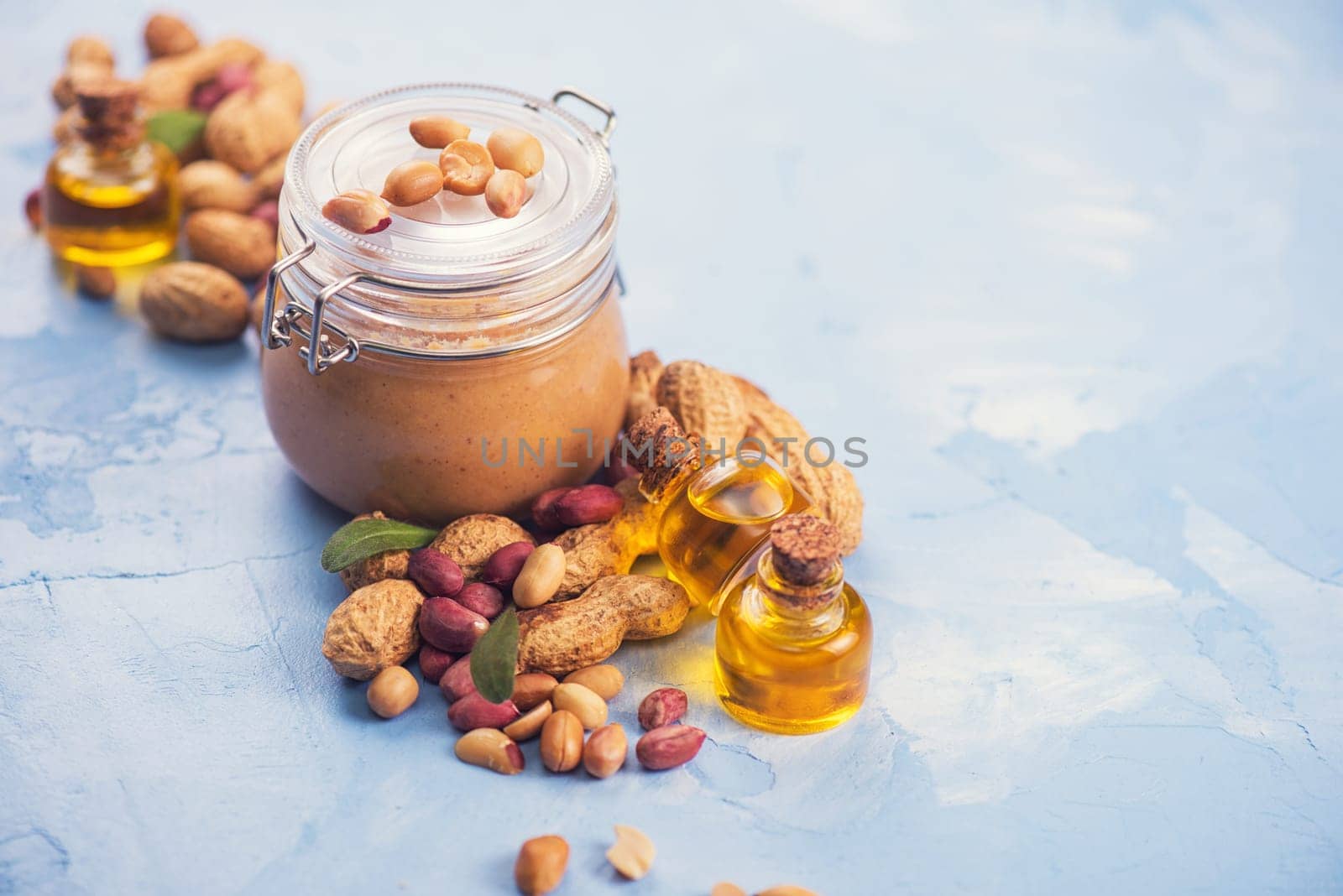 Natural peanut butter with oil in a glass jar and peanuts