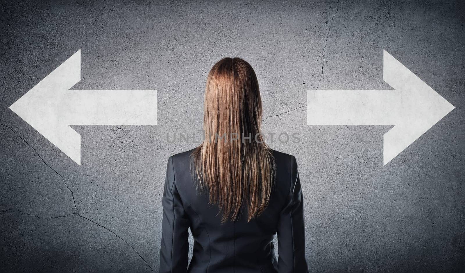 Rear view doubtful businesswoman in front of a cracked concrete wall with painted arrows pointing on two different directions. Choose between left and right sides, business failure or success concept